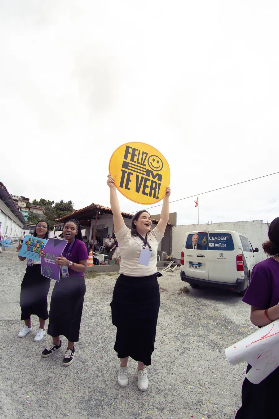 Equipe de recepção com placa "Feliz em te ver" na chegada dos congressistas