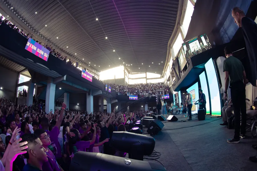 Vista do palco para a plateia de mãos levantadas, com a banda tocando